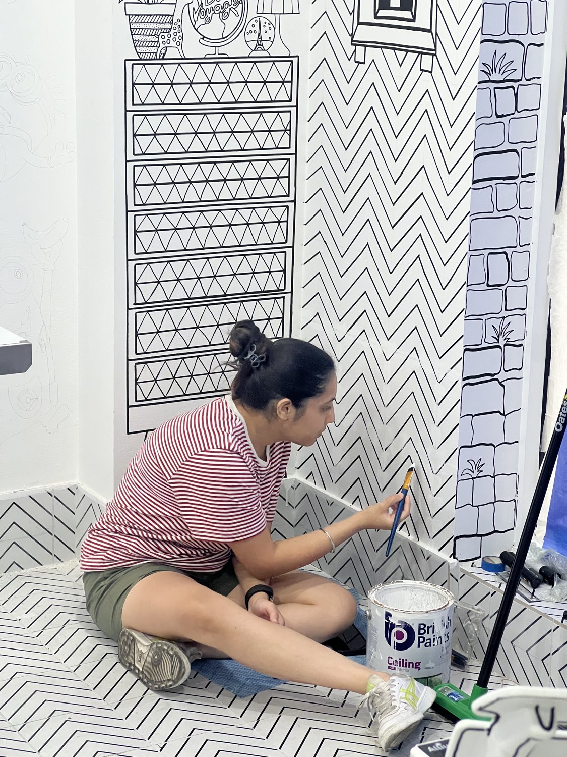 Hirwa Darji hand-painting the 2D mural on the cafe wall